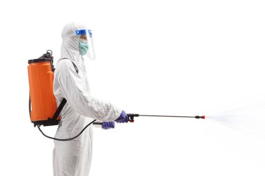 Tehlikeli madde giysisi giymiş bir uzmanın profil fotoğrafı beyaz arka planda izole edilmiş bir dezenfektan püskürtüyor.