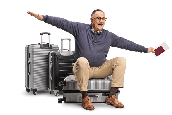 一个成熟的男人坐在手提箱上 为被白色背景隔离的飞行做着手势 — 图库照片