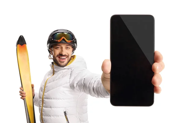 白い背景に隔離されたカメラの前でスマートフォンを持って幸せな男性スキーヤー — ストック写真