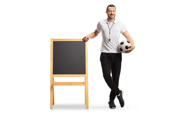 体育教師はサッカーを持ち 白地に隔離された黒板にもたれている — ストック写真