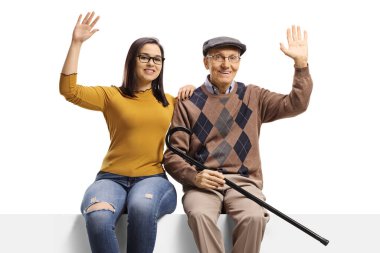 Büyükbaba ve torun boş bir panelde oturuyor ve beyaz arka planda izole edilmiş kameraya el sallıyorlar.