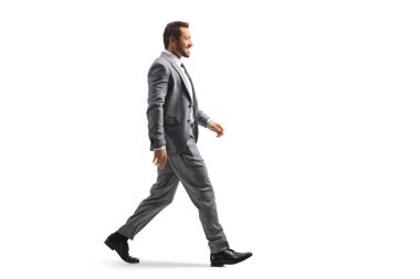 Beyaz arka planda tek başına yürüyen genç bir adamın tam boy profil çekimi.