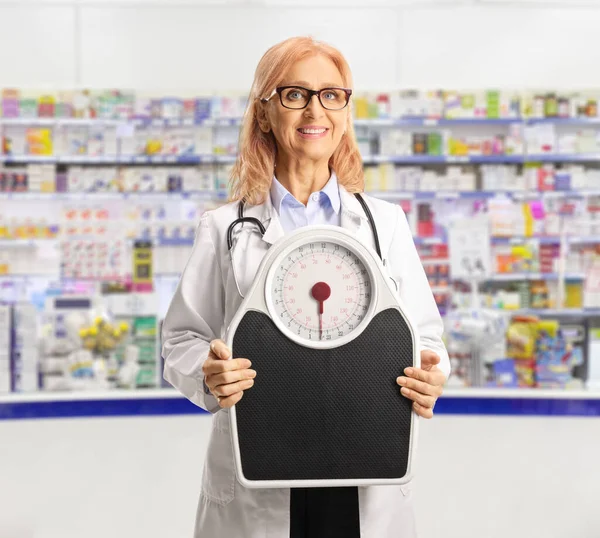 Smiling female doctor holding a weight scale inside a pharmacy
