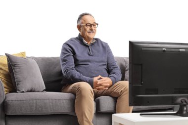 Smiling mature man sitting on a sofa and watching tv isolated on white background