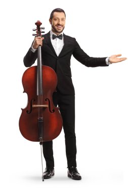 Full length portrait of a young male artist posing with a cello and showing with hand isolated on white background