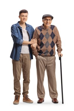 Full length portrait of a guy helping an elderly man walking with a cane isolated on white background