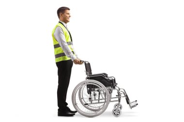 Full length profile shot of a security guard standing behind a wheelchair isolated on white background