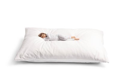 Little girl in pajamas sleeping a big soft pillow isolated on white background