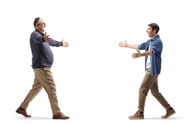 Full length profile shot of a young man walking towards a mature man with arms wide open isolated on white background