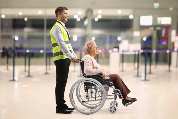 Assitance worker helping an elderly woman in a wheelchair at the airport