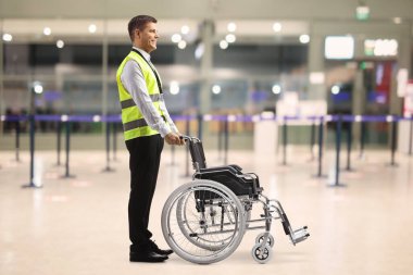 Male assitance worker at the airport standing with a wheelchair