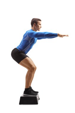 Full length portrait of a step aerobic instructor doing an exercise isolated on white background