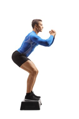 Full length portrait of a male step aerobic instructor showing an exercise isolated on white background