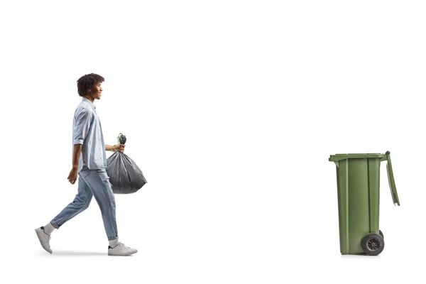 一个非洲裔美国人走向一个垃圾桶 提着一个用白色背景隔开的塑料垃圾袋 照片全长拍摄 — 图库照片