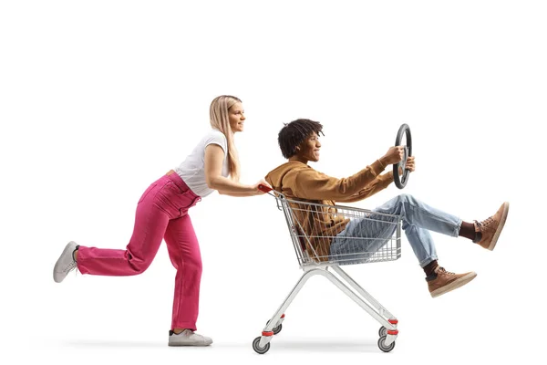 Young Caucasian Woman Pushing African American Guy Shopping Cart Isolated — Stok fotoğraf