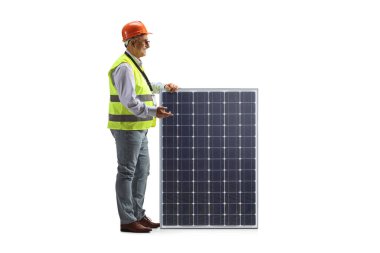 Mature male engineer with a vest and hardhat standing next to a photovoltaic panel isolated on white background