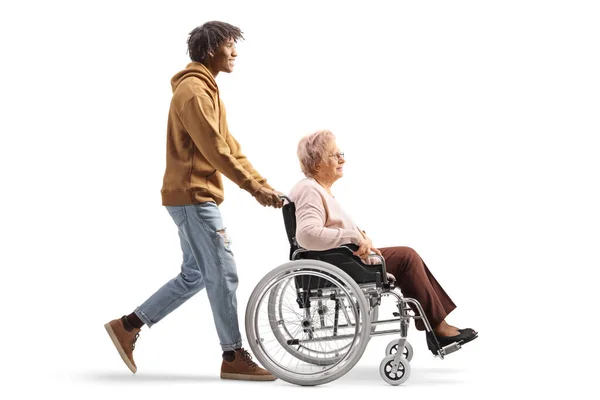 一名非洲裔美国青年男子推着一名坐在轮椅上的老年妇女在白色背景下被隔离的全景照片 — 图库照片