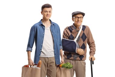 Young man helping an elderly man with a broken arm and carrying shopping bags isolated on white background