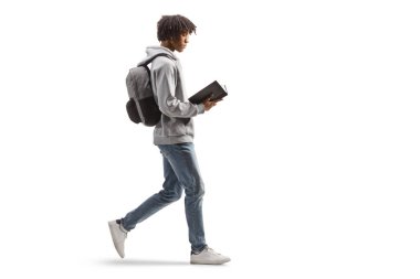 Full length profile shot of a young african american man walking and reading a book isolated on white background