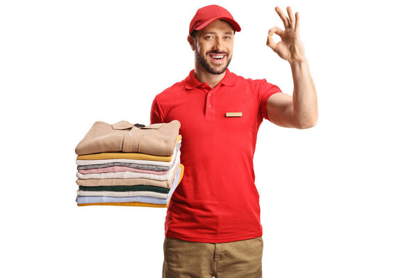 Male worker holding a pile of folded clothes and gesturing great isolated on a white backgroun