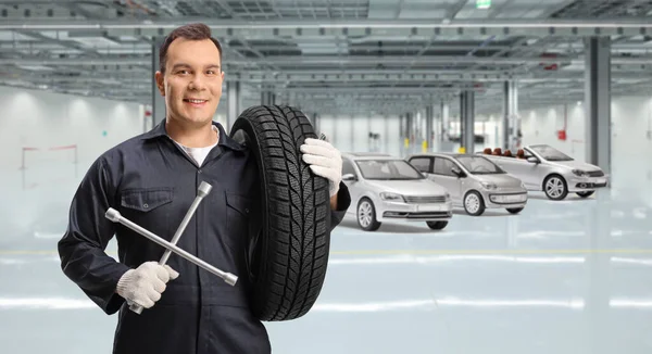 Automechaniker Mit Einem Reifen Und Einem Schraubenschlüssel Einer Autowerkstatt — Stockfoto