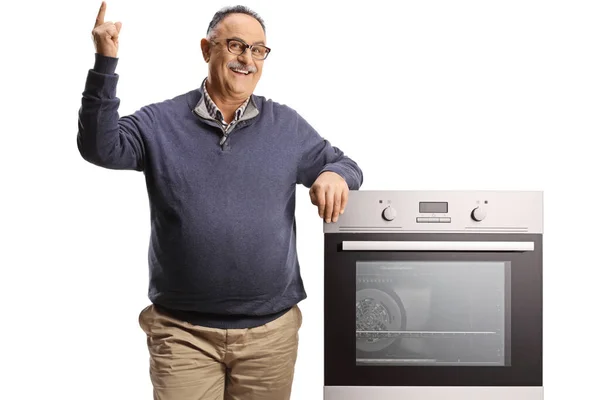 Smiling Mature Man Leaning Oven Pointing Isolated White Backgroun — Stockfoto