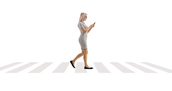 白い背景に隔離された歩行者用交差点でスマートフォンを使用して歩く若い女性 — ストック写真