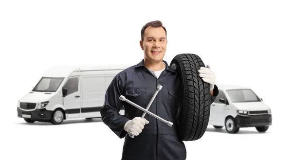 汽车修理工在面包车前摆姿势 拿着轮胎和扳手工具 与白色背景隔离 — 图库照片