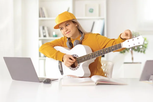 Молодая Женщина Учится Играть Акустической Гитаре Перед Ноутбуком Дома — стоковое фото