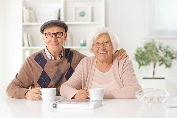 Szczęśliwa Para Starców Siedzi Domu Filiżankami Herbaty Uśmiecha Się Kamery — Zdjęcie stockowe