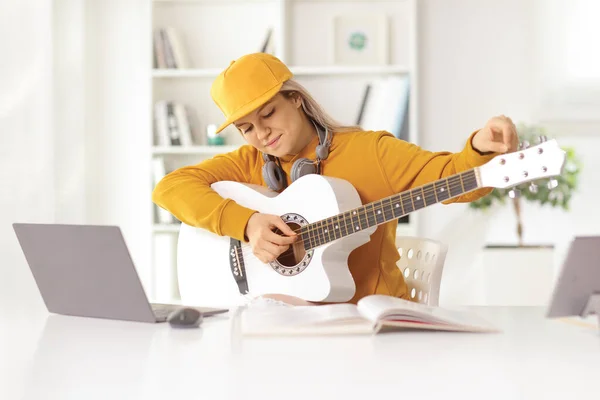 Młoda Kobieta Stroi Gitarę Akustyczną Przed Laptopem Domu — Zdjęcie stockowe
