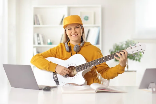 Młoda Kobieta Gitarą Akustyczną Siedząca Przed Laptopem Domu Uśmiechnięta Kamery — Zdjęcie stockowe