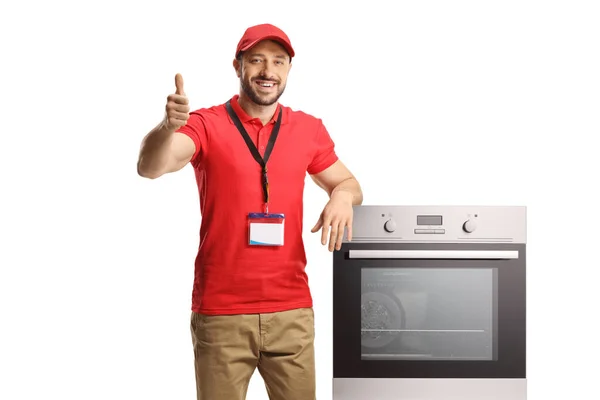 售货员靠在烤箱上 用白色背景隔绝的大拇指做手势 — 图库照片