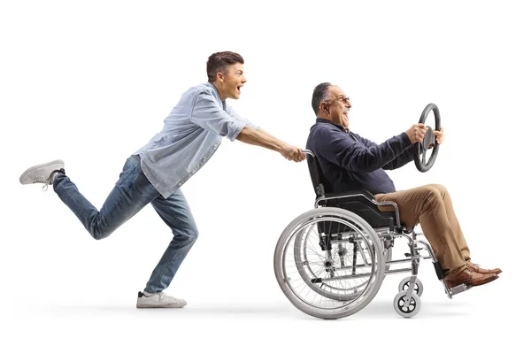 一个人推着一个坐在轮椅上的成熟男人 手里拿着一个白色背景的方向盘 拍摄了全长的轮廓 — 图库照片