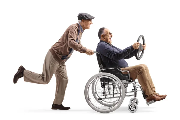 車椅子の男を押している高齢者のフル長プロファイルショット白い背景に隔離されたステアリングホイールを保持 — ストック写真