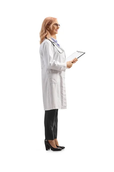 白い背景に隔離されたクリップボードを持つ文書を保持している女性医師の完全な長さプロファイルショット — ストック写真