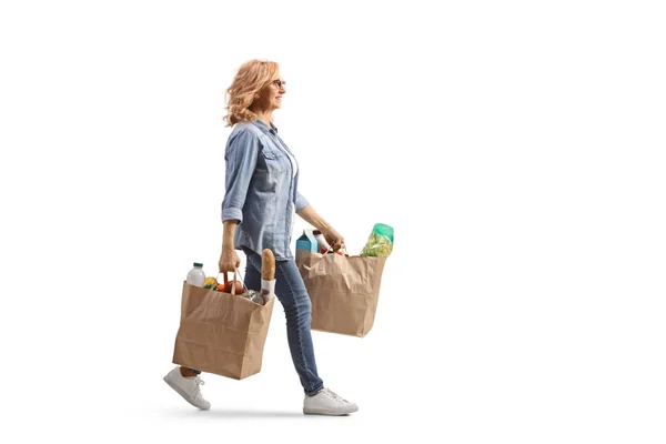 フル長さプロフィールショットの成熟した女性持っ食料品袋と歩行隔離された白の背景 — ストック写真
