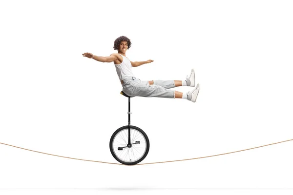 非洲裔美国男性杂技演员骑单轮坐在一根被白色背景隔离的绳子上 — 图库照片