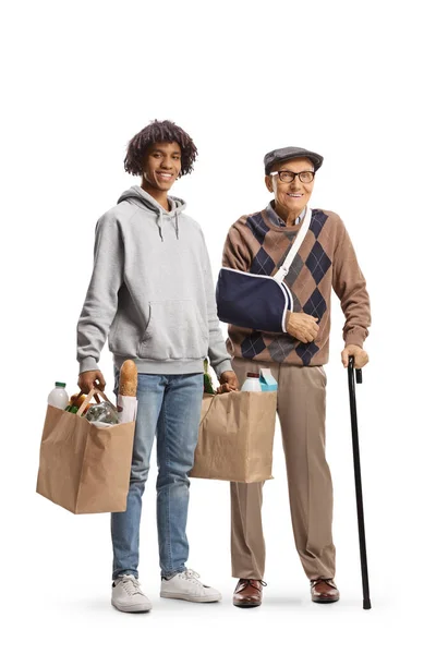 年轻的非洲裔美国人 为一个手臂断了 背景为白色的老年男子提着购物袋 — 图库照片