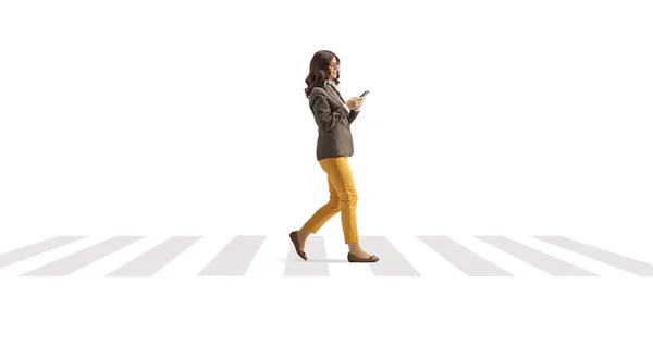白い背景に隔離された横断歩道を歩くスマートフォンを持つ若い女性 — ストック写真