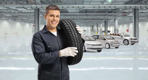 Automechaniker Trägt Einen Reifen Auf Der Schulter Und Lächelt Einer — Stockfoto