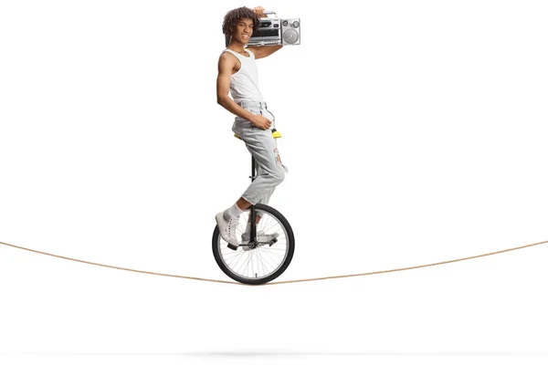 一个非洲裔美国人骑着单骑自行车坐在绳子上 手里拿着一个用白色背景隔开的保险盒 — 图库照片