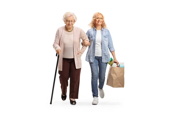 女性の完全な長さの肖像画は 高齢者の女性を助け 白い背景に隔離された食料品袋を運ぶ — ストック写真