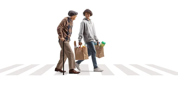 白い背景に隔離された横断歩道で食料品袋を持つ高齢者を助ける若いアフリカ系アメリカ人男性 — ストック写真