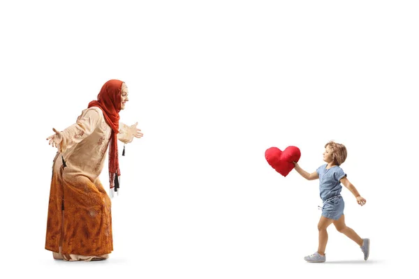 赤いハートを持ち 白い背景に孤立したヒジャーブを身に着けているイスラム教徒の女性に向かって走っている女の子 — ストック写真