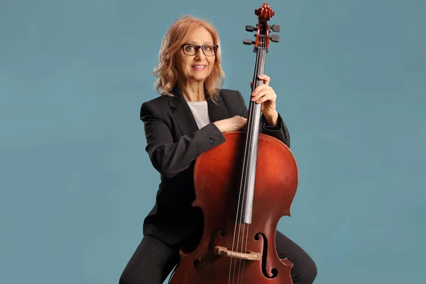 Volwassen Vrouwelijke Kunstenaar Zitten Poseren Met Een Cello Geïsoleerd Blauwe — Stockfoto