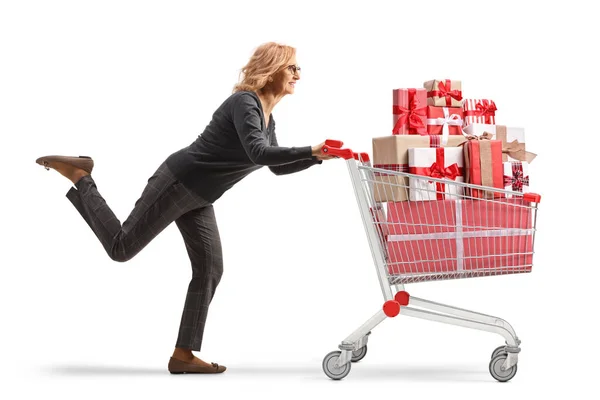 白い背景に隔離されたギフトボックスでいっぱいのショッピングカートで走っている女性の完全な長さのプロフィール写真 — ストック写真