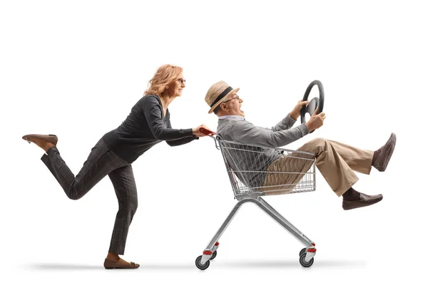白い背景に隔絶されたハンドルを握るショッピングカートの中で老人を押す女性 — ストック写真