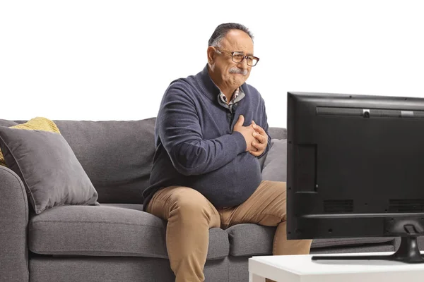 Dojrzały Mężczyzna Siedzi Kanapie Mając Atak Serca Przed Telewizorem Odizolowany — Zdjęcie stockowe