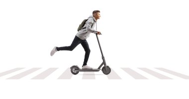 Sırt çantalı bir erkek öğrencinin beyaz arka planda izole edilmiş bir şekilde yaya zebra geçidinde elektrikli scooter sürerken tam boy görüntüsü.